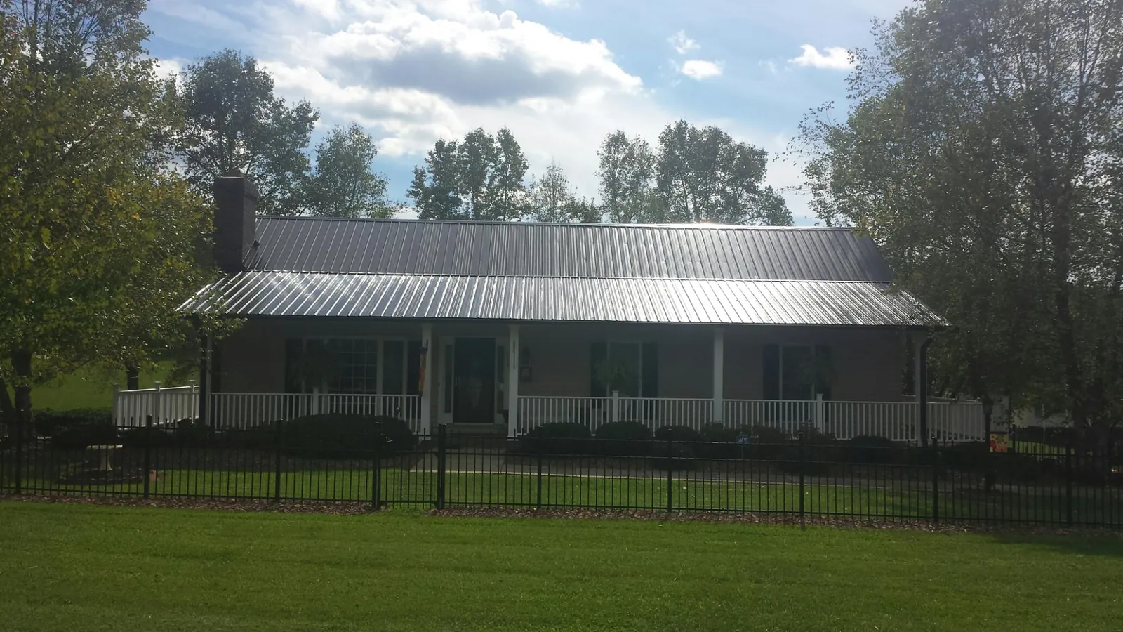 Gray metal roof on a brick ranch with a full width front porch — Gutter Guard Installation work by our crew in Tracy City