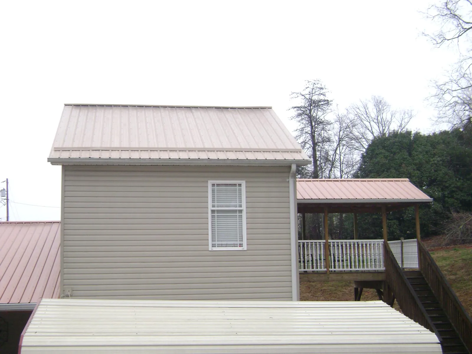 Tan metal roofs on a two story addition and attached porch, from a Roof Replacement job in Tracy City