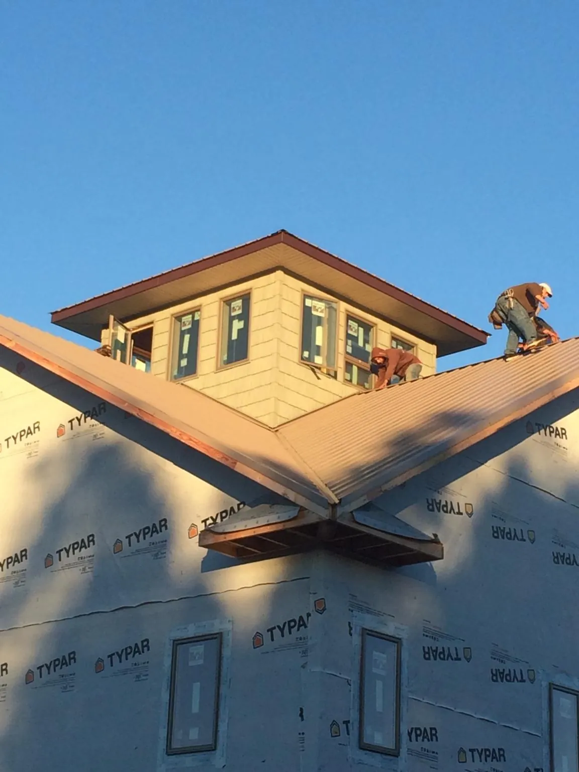 Roofers working around a rooftop cupola on a new metal roof at sunset — Roof Waterproofing in Tracy City by Roofing Brothers